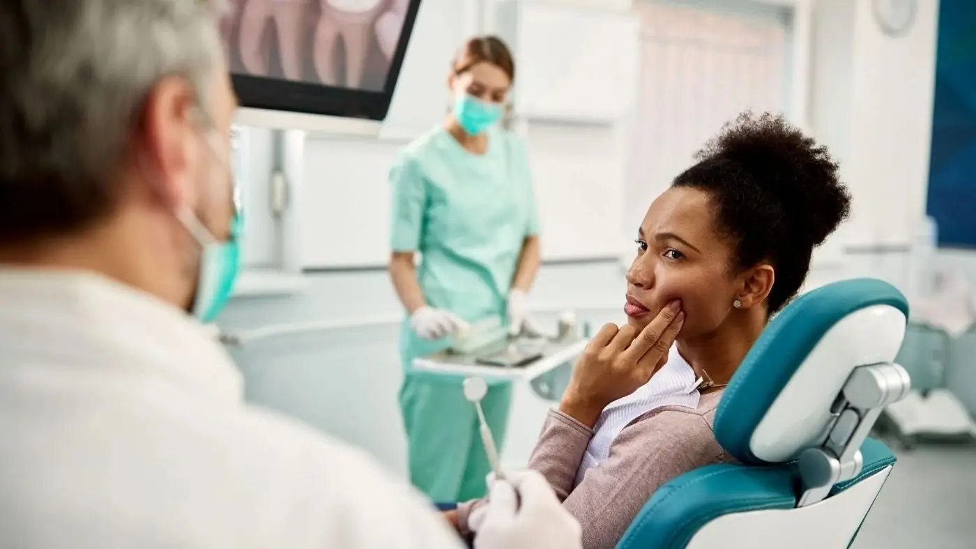 Patient holding her jaw while describing TMJ pain at Olympic Park Smiles Dental in Calgary